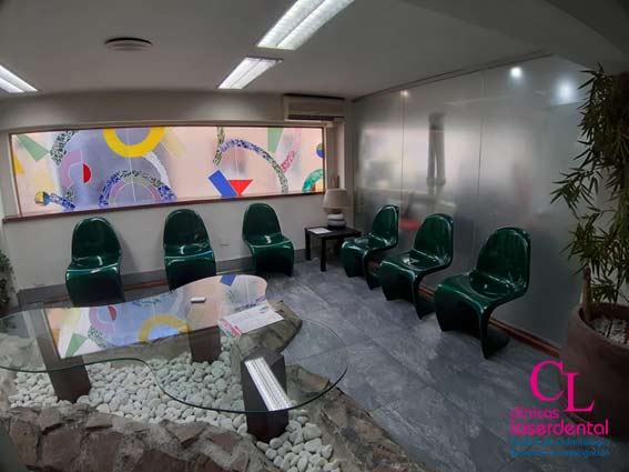 Sala de espera de la planta segunda de la clinica con sillas para la espera de los pacientes y una mesa de cristal que esta metida en una fuente de agua